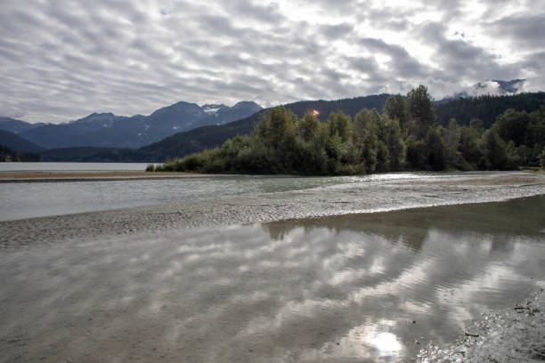 istock View across reflection of clouds and forest to mountains and sky 1283162267