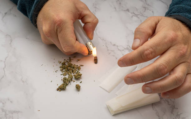 istock Caucasian man setting fire to the hashish to mix it with marijuana and make a cigar 1283164397