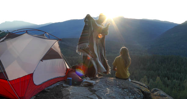 istock Young man brings blanket to girlfriend at campsite 1283165949