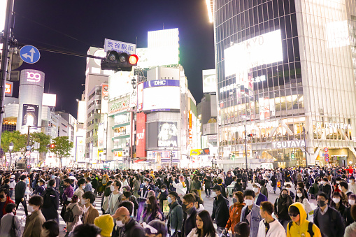 Tokyo, Japan - October  31 2020:  Massive Crowds of People gather close to Shibuya station and Shibuya Scramble crossing to celebrate the Halloween.  While covid-19, people wearing costumes and Protective Face Mask.  All Shibuta streets are very busy by many people gathering and screaming.  The police alert for safety to young people till late night.  It is one of the social issue recent years in Shibuya Tokyo Japan.