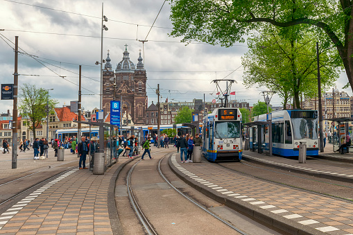 Street scene from near central station in Amsterdam. People and trams in the background.