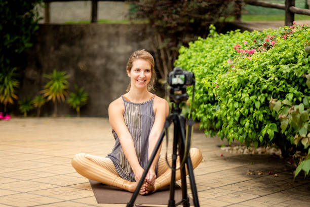istock Instructor woman teaching yoga sitting in the backyard, filming an online class 1283170884