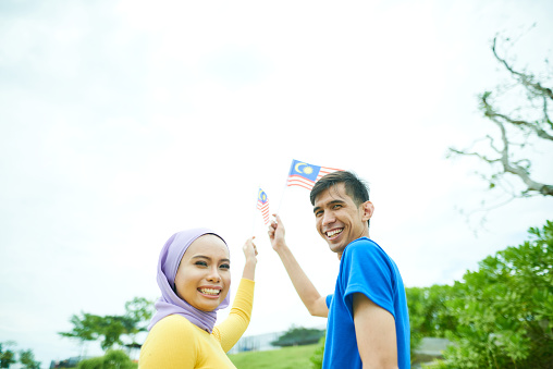 Happy Malaysian couple holds Malaysian flag during independence day celebration