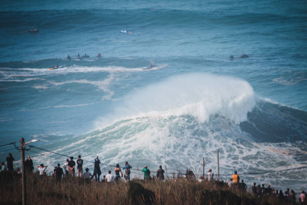 Crowd on cliff at North Beach waves impressive swell and waves of courages surfers, Portugal Nazare, Portugal - October 29, 2020: Crowd on cliff at North Beach waves impressive swell and waves of courages surfers, Portugal nazare surf stock pictures, royalty-free photos & images
