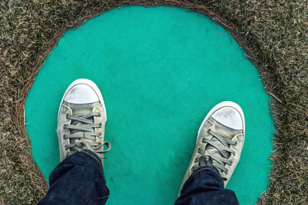 Man wearing blue jeans, sneakers and stepping on the circle.