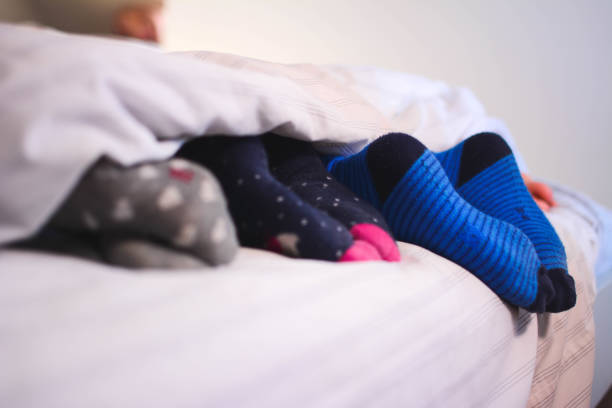 istock Legs with colorful socks on bed 1283176174