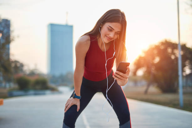istock Modern young woman with cellphone making pause during jogging / exercise. 1283176348