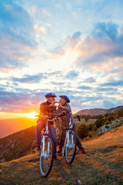 istock Active Senior Couple on bikes making heart shape with hands and kissing. 1283178263