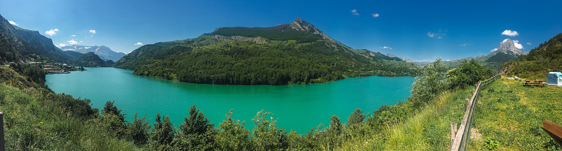 Mountain lake with a hill in the background and blue sky and a lot of trees