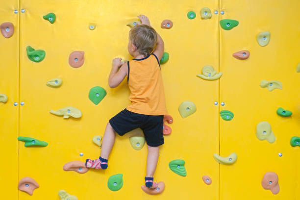 Little active boy rock climbing at indoor gym
