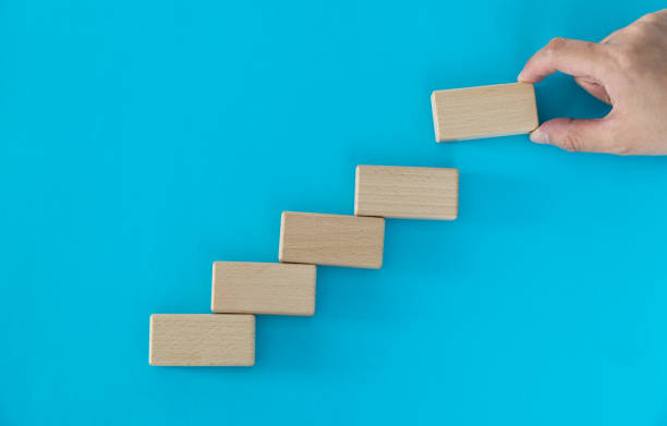 istock Human hand building stairs with blocks 1283181102