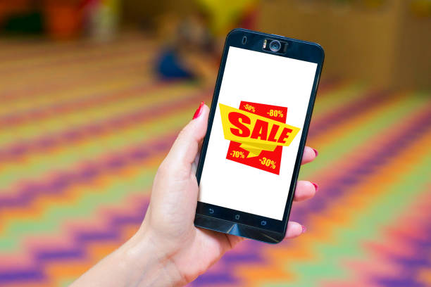 istock Hand holding mobile phone with sale sign 1283181950