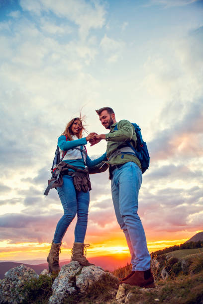 istock Couple on Top of a Mountain Shaking Raised Hands 1283182006