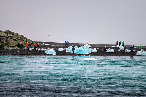 Jokulsarlon, Iceland - June 15, 2018: Glacial lagoon lake river with many icebergs floating on water with people tourists