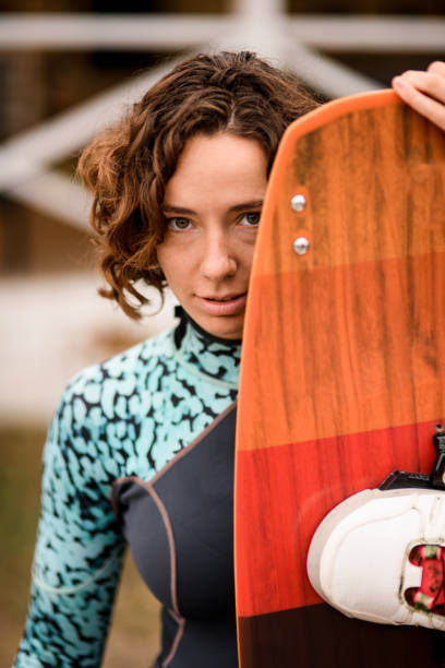 istock Young beautiful woman peeks out from behind wakeboarding board. 1283188895