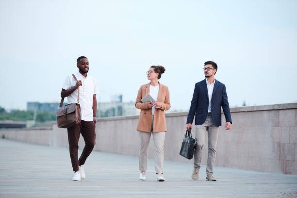 istock Three young intercultural business partners moving down road in front of camera 1283189136