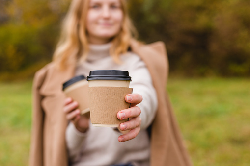 Woman holds two paper coffee cups. Take away or delivery concept. Copy space. Autumn lifestyle. Place for your text or logo on mug