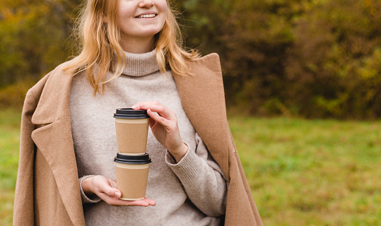 Woman holds two paper coffee cups. Take away or delivery concept. Copy space. Autumn lifestyle. Place for your text or logo on mug