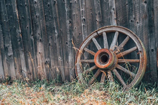 istock One rusty wagon wheels against a wooden wall, with grass. Useful for rustic backgrounds 1283190249