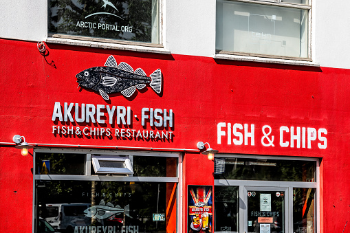 Akureyri, Iceland - June 17, 2018: Small town village city with fish and chips restaurant chip seafood shop entrance red building color