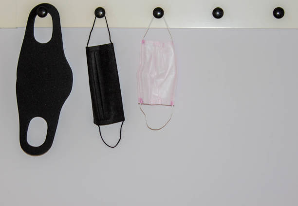 istock protective face masks hanging on wall for going back to work or back to school for easy access with copy space. Wearing mask concept. Black 1283193036