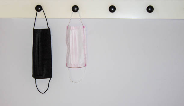 istock protective face masks hanging on wall for going back to work or back to school for easy access with copy space. Wearing mask concept. Black 1283193066