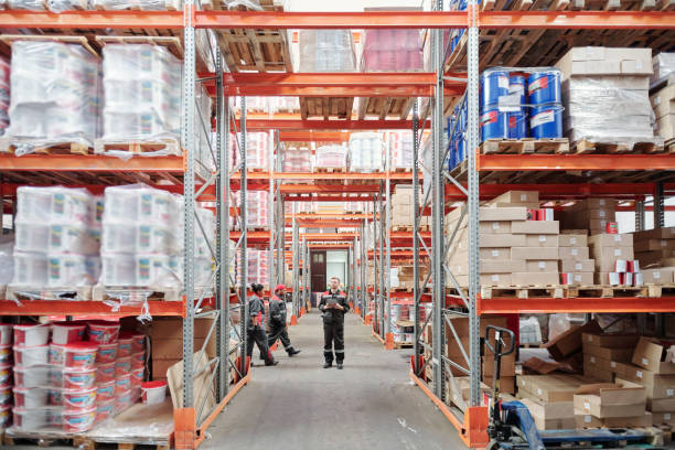 istock Young intercultural warehouse workers in uniform moving along large racks 1283204020