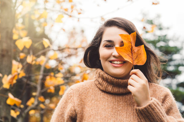 istock Smiling happy woman holding a leaf in front her face 1283205374