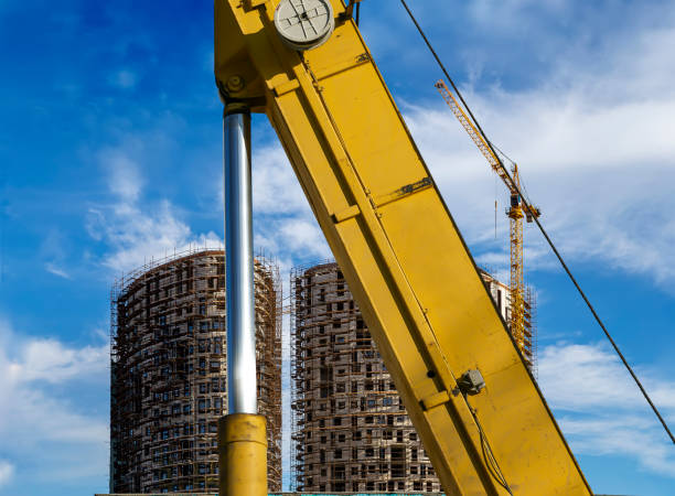 istock Part of a construction machine (excavator or crane) with multi-storey building under construction with scaffolding (new residential complex) on the background, Moscow, Russia 1283205574