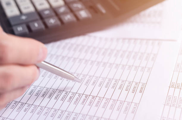 istock Accounting concept. male hand closeup with pen over financial documents with blurred calculator on background 1283206994