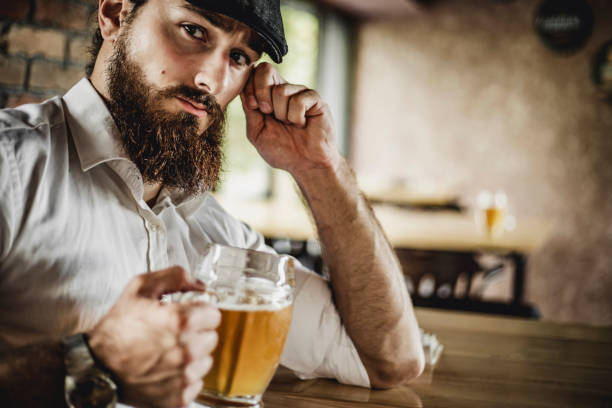 Happy bearded man who drinks beer in the pub - Young hipster man - Portrait of a young man with a beard holding a beer