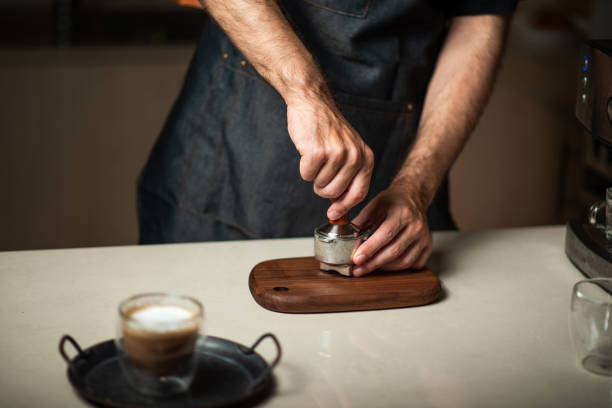 istock Man tampering coffee powder into the portafilter while making coffee 1283207297