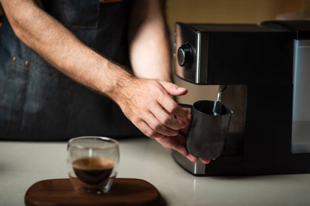istock Man steaming the milk in a metal jar for making a cappuccino 1283207359