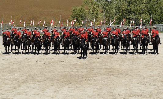 Ancaster, ON Canada - September 24, 2016: officers in red RCMP uniforms on horseback holding flags, inspection line up; during a RCMP musical ride presentation during the Ancaster Fair in Ontario Canada