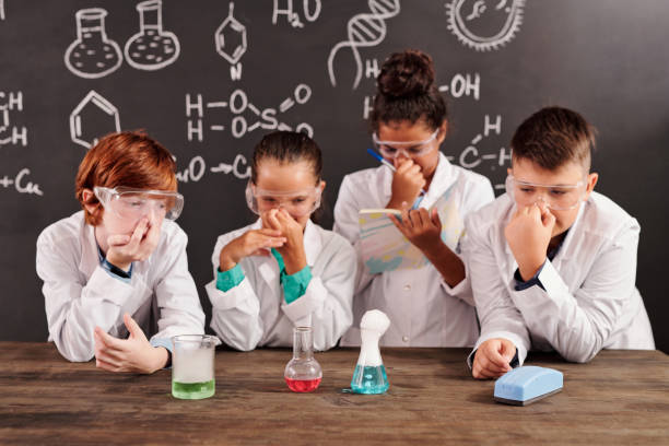 istock Cute schoolkids in protective eyeglasses plugging noses while watching reactions 1283210939