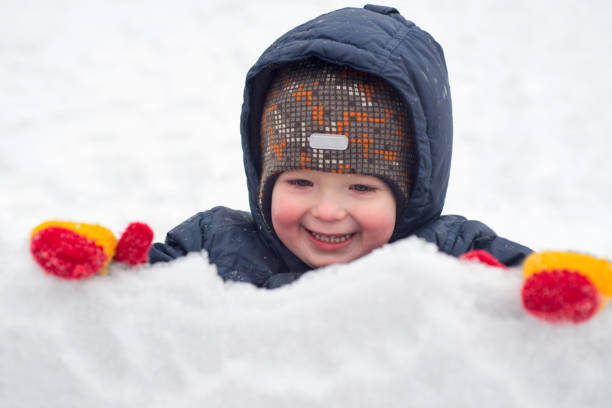 uma criança brinca com neve ou pedaços de gelo ao ar livre no inverno. uma atividade infantil no inverno - playground snow winter little girls - fotografias e filmes do acervo