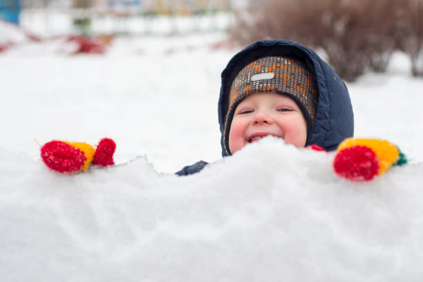 маленький ребенок играет со снегом или кусочками льда на открытом воздухе в зимний период. детская деятельность зимой - playground snow winter little girls стоковые фото и изображения
