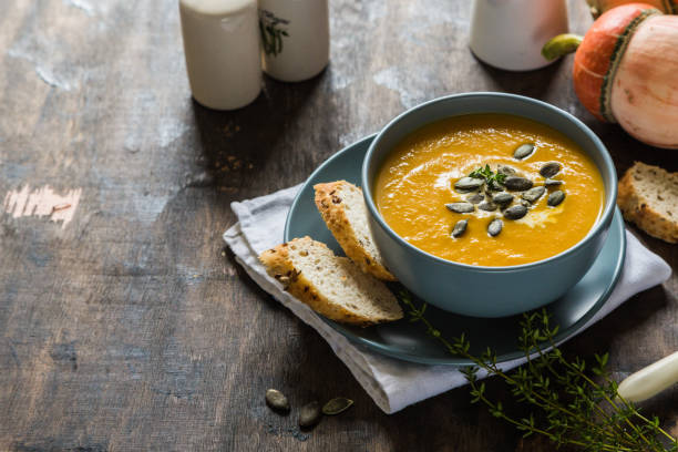 pumpkin and carrot cream soup with pumpkin seeds and toasted bread stock photo