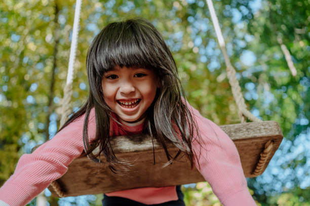 Autistic korean girl swinging on a swing outdoors stock photo