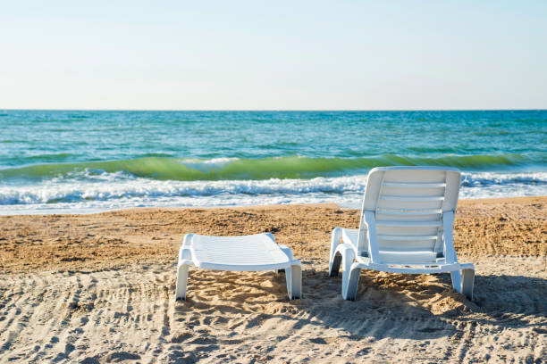 two deckchairs on a beach, facing out to sea