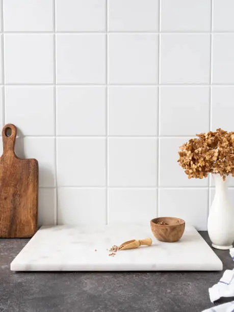 Stylish white kitchen background with brown kitchen utensils and decor standing on textupe grey countertop, copy space, front view