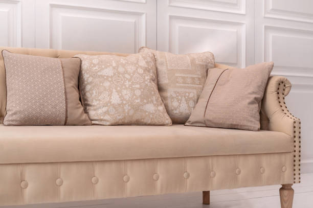 istock Appartment design elements: beige cushions with Christmas pattern on beige old style couch in white room 1283222442