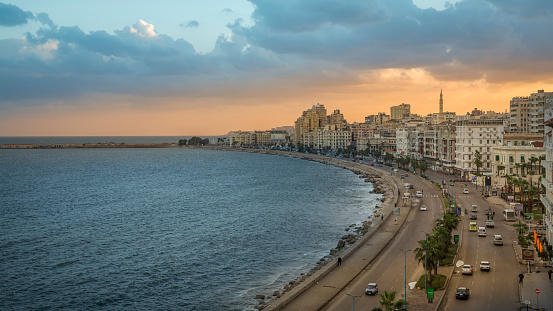 Alexandria, Egypt - November 15, 2018 :  \n\nOn the edge of the mediterranean sea, we find the corniche of alexandria. It is one of the main traffic corridors in the city and a wonderful walk especially at sunset. There are many hotels, restaurants and cafes along the corniche,  This cosmopolitan city has unequivocally a mythical aura.