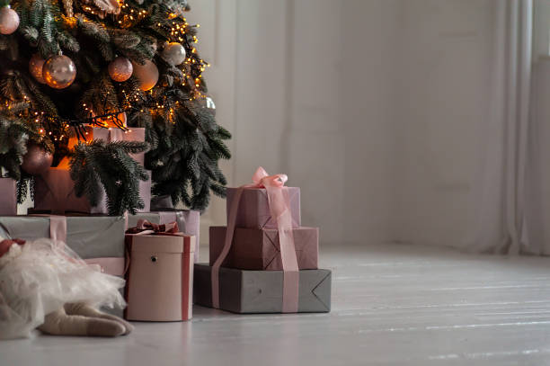 Gifts boxes under decorated Christmas tree in white room with white wooden floor Gifts boxes under decorated Christmas tree in white room with white wooden floor pink christmas tree stock pictures, royalty-free photos & images