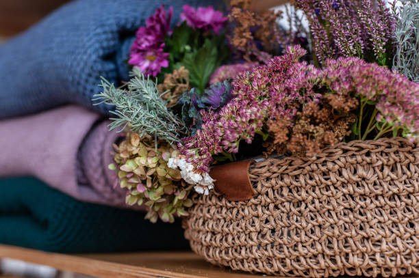 istock Stack of warm colorful blankets near rustic knitted basket with autumn flower composition 1283227243