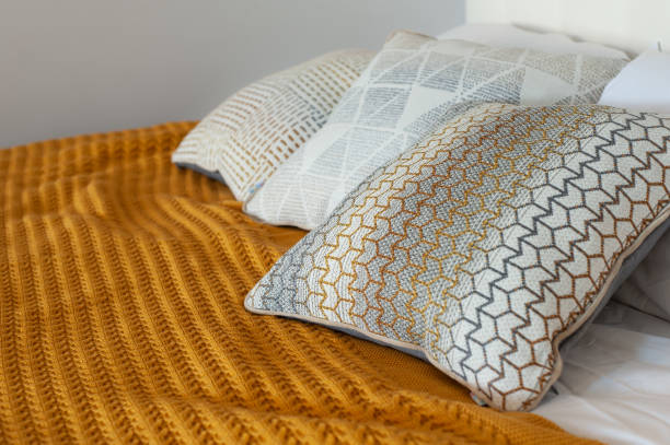 istock Gorgeous yellow knitted blanket on bed in cozy bedroom 1283228342