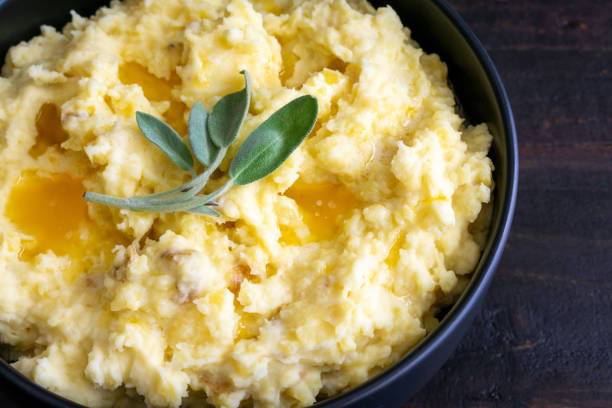 Mashed Potatoes Topped With Butter and Sage Leaves Mashed Yukon gold potatoes with peels topped with melted butter and a sprig of fresh herbs mashed potatoes stock pictures, royalty-free photos & images
