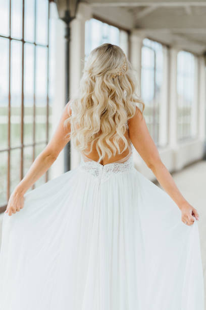 feliz novia bonita mostrando su vestido de novia de su espalda. boda y momentos felices de una mujer - bride veil women human face fotografías e imágenes de stock