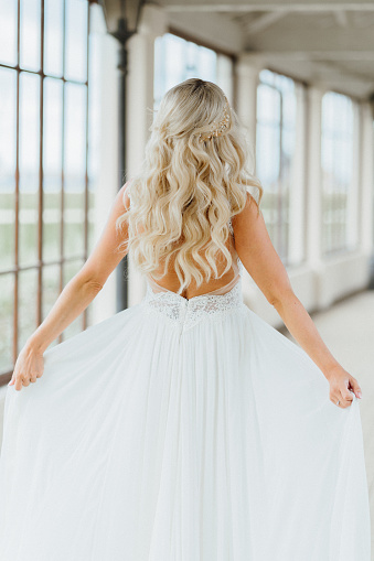 Happy pretty bride showing her wedding dress from her back. Wedding and happy moments of a woman.
