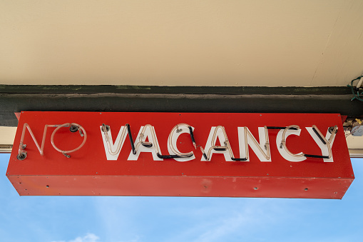 Red retro no vacancy neon sign, during daytime